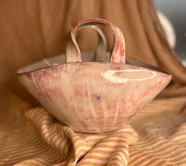 Håndlaget veske-vase i beige og rødrosa glasur laget av Caroline Sagafos.