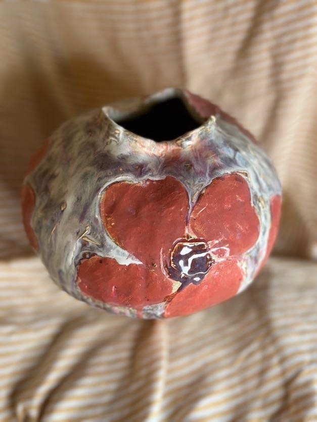 Stor håndlaget keramikkvase med blomsterrelieff i røde og lilla glasurtoner, laget av Caroline Sagafos.