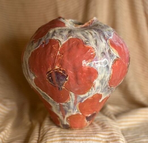 Stor håndlaget keramikkvase med blomsterrelieff i røde og lilla glasurtoner, laget av Caroline Sagafos.