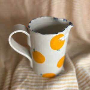 Håndlaget keramikkmugge med håndmalte appelsiner og blå detaljer, laget av Caroline Sagafos på Bekkelund Gård & Keramikk.