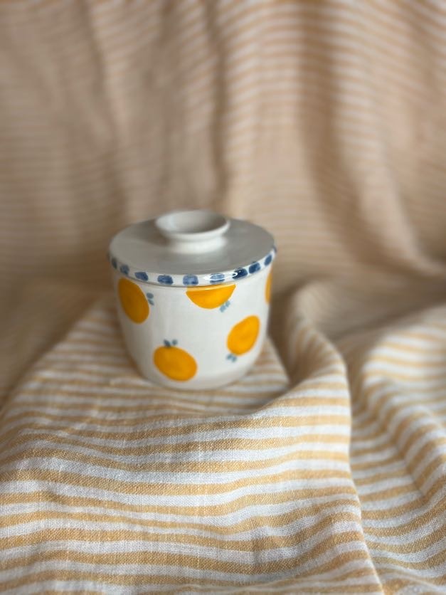Håndlaget keramikk-smørklokke med hvit glasur, håndmalte appelsiner og blå prikker på lokket, laget av Caroline Sagafos.