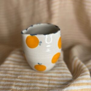 Liten håndlaget fløtemugge i keramikk med appelsinmotiv og blå detaljer, laget av Caroline Sagafos.