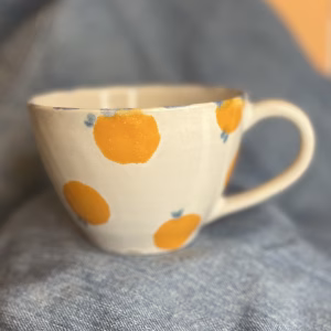 Håndlaget tekopp med håndmalte appelsiner i guloransje og små blå detaljer.