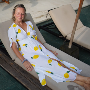 Caroline i sitronmønstret bomullskjole, liggende på solseng i solen.