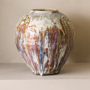 Håndlaget kunstvase med flytende glasur i kremhvite, lilla og varme toner.