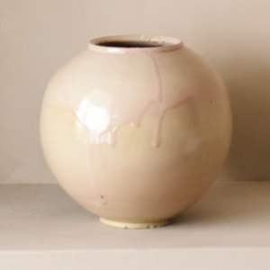 Håndlaget rund kunstvase med kremhvit og myk rosa glasur.