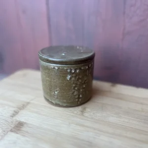 Håndlaget smørklokke i varm brun glasur med dekorative organiske detaljer.