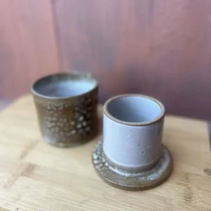 Håndlaget smørklokke i beige og brun glasur med dekorative mønstre og keramisk lokk.